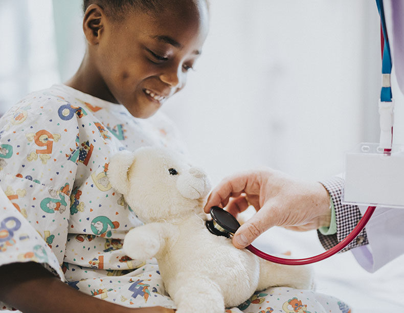 Doctor playfully checking the heart beat of a teddy bear